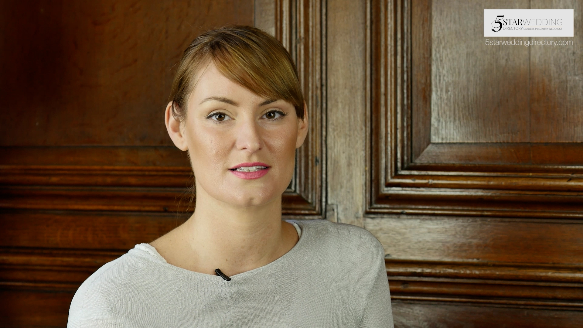 A woman in a well-lit interview set-up against a panelled wood backdrop